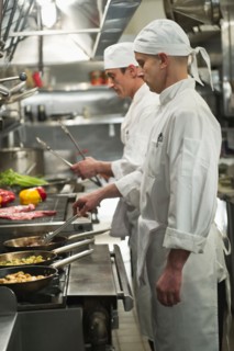 Chefs preparing food in kitchen.