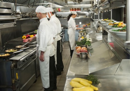 Chefs preparing food in kitchen.