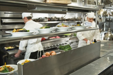 Chefs preparing food in kitchen.