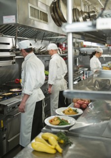Chefs preparing food in kitchen.