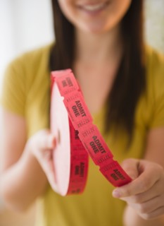 Close up of woman holding tape with "admit one" tickets in roll. Photo : Jamie Grill Photography