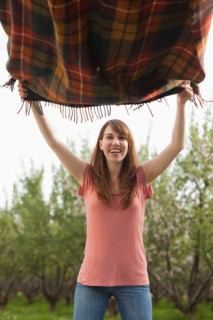 Young woman holding blanket in orchard. Photo : Mike Kemp