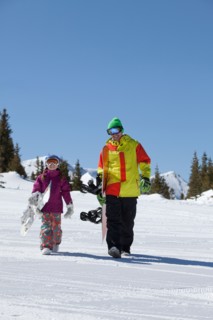 USA, Colorado, Telluride, Father and daughter (10-11) walking with snowboards in winter scenery.