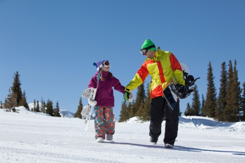 USA, Colorado, Telluride, Father and daughter (10-11) walking with snowboards in winter scenery.