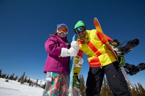 USA, Colorado, Telluride, Father and daughter (10-11) posing with snowboards in winter scenery.