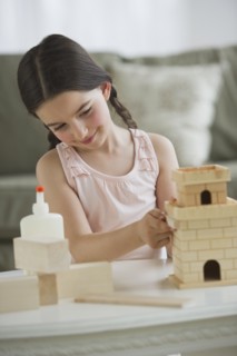 Girl (8-9) building toy castle.