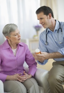 Smiling doctor giving medicine bottle to senior woman.