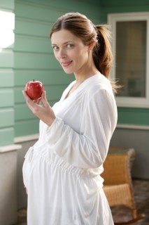 Portrait of expecting mother eating apple. Photo : Rob Lewine