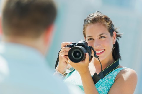 Portrait of young woman taking pictures with camera.