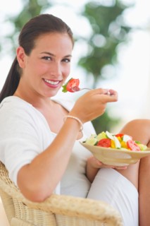 Portrait of young woman eating salad.