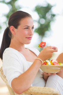 Portrait of young woman eating salad.
