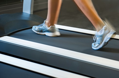 Low section of woman walking on treadmill.