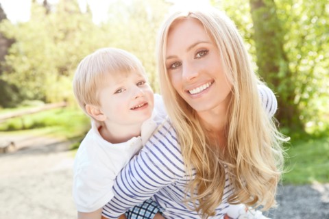 Young woman giving piggyback ride to son (2-3) in park. Photo : Take A Pix Media