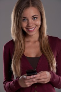 Portrait of teenage girl (16-17) with mobile phone, studio shot. Photo : Rob Lewine
