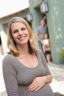 Portrait of pregnant mother with family in background. Photo : Rob Lewine