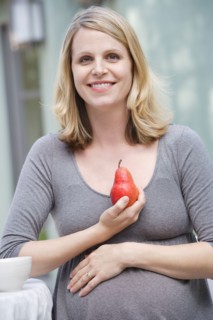 Pregnant woman holding pear. Photo : Rob Lewine