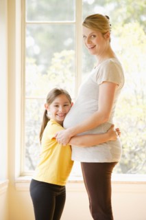 Daughter (6-7) embracing pregnant mother. Photo : Rob Lewine