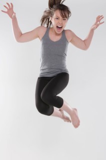 Portrait of young woman jumping, studio shot. Photo : Rob Lewine