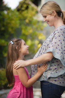 Pregnant mother standing face to face with daughter (6-7) . Photo : Rob Lewine