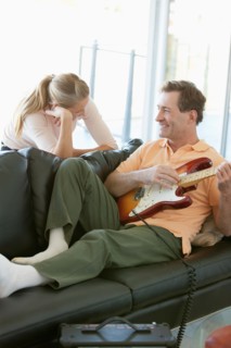 Mature man playing guitar while woman listening. Photo : Rob Lewine