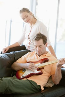 Mature man playing guitar while woman listening. Photo : Rob Lewine