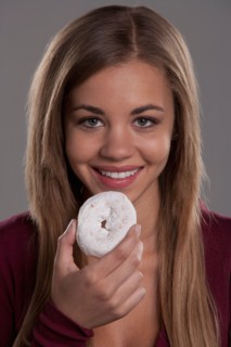 Portrait of teenage girl (16-17) with donut, studio shot. Photo: Rob Lewine