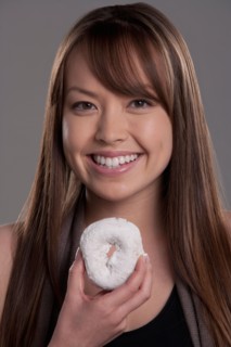 Portrait of young woman with donut, studio shot. Photo: Rob Lewine