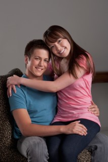 Portrait of teenage boy (16-17) embracing with young woman, studio shot. Photo : Rob Lewine