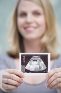 Pregnant woman holding CAT image of her belly. Photo : Rob Lewine