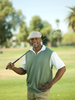 Smiling man on golf course holding golf club. Photo : db2stock