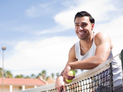 Smiling man standing near tennis net. Photo : db2stock