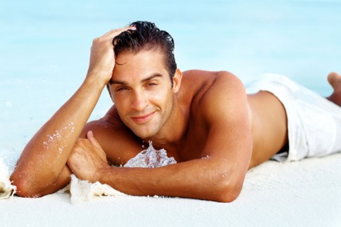 Smart young man relaxing on beach. Photo : momentimages