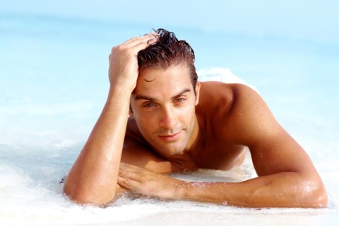 Portrait of attractive young man relaxing on beach. Photo : momentimages