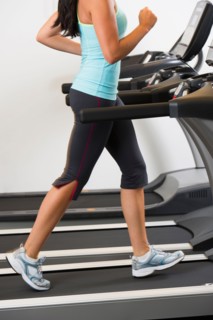 Low section of woman walking on treadmill.