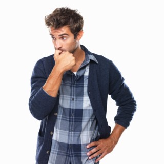 Studio shot of young man biting nails and looking away. Photo : momentimages