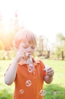 Boy (2-3) blowing bubbles in park. Photo: Take A Pix Media