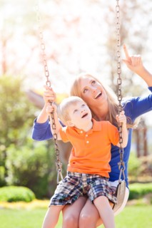 USA, Washington State, Seattle, Mother and son (2-3) swinging on swing in park. Photo : Take A Pix