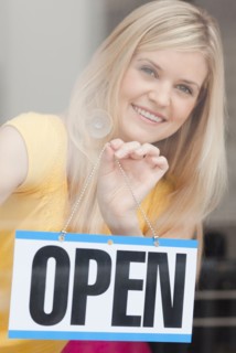 Portrait of young woman hanging sign in window. Photo : Jamie Grill