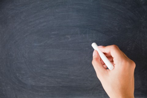 Close up of woman's hands writing with chalk on blackboard. Photo : Jamie Grill