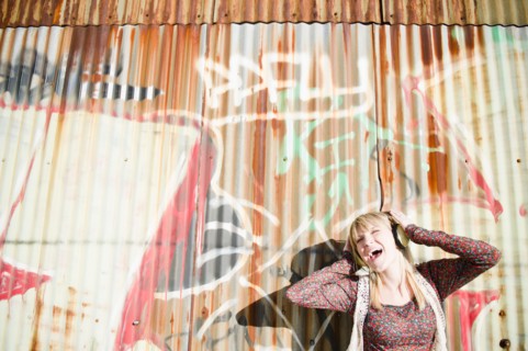 USA, Brooklyn, Williamsburg, Portrait of woman with headphones against graffiti wall. Photo : Jamie