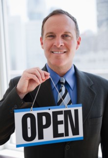 Businessman holding open sign. Photo : Jamie Grill