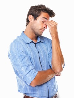 Studio shot of young business man with eyes closed rubbing nose. Photo: momentimages