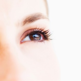 Studio shot of young woman, close-up of eye.