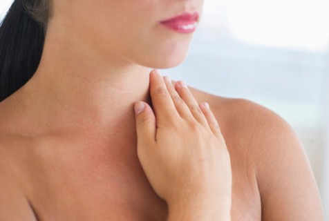 Young woman with hand on neck.