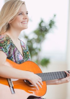 Young woman playing guitar. Photo : Jamie Grill