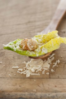 Fresh caesar salad on wooden spoon.