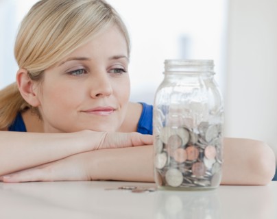Young woman looking at jar with coins in it. Photo: Jamie Grill