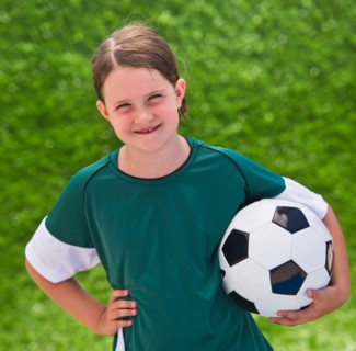 Portrait of girl (6-7) with soccer ball. Photo : Daniel Grill