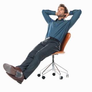 Studio shot of young business man relaxing on chair with hands behind head. Photo : momentimages