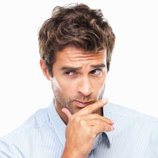 Close-up portrait of confused business man with had on chin against white background. Photo: